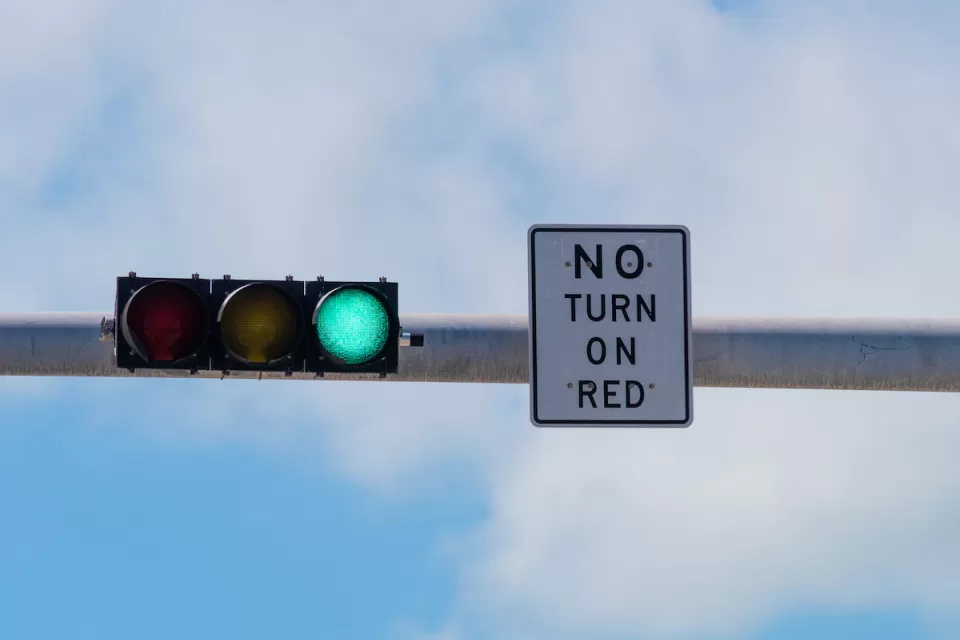 Overhead traffic light with green light on and white "No turn on red" sign.